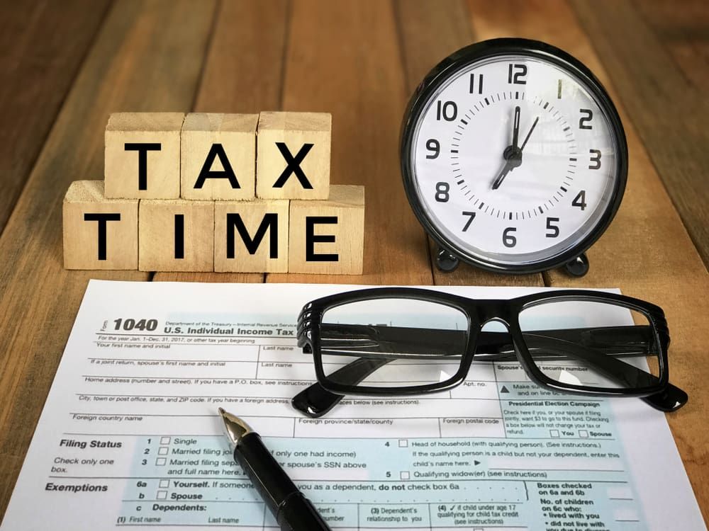A Clock, Glasses, a Pen and A Tax Form on A Wooden Table — Catalyst Accounting & Tax in Killarney, QLD