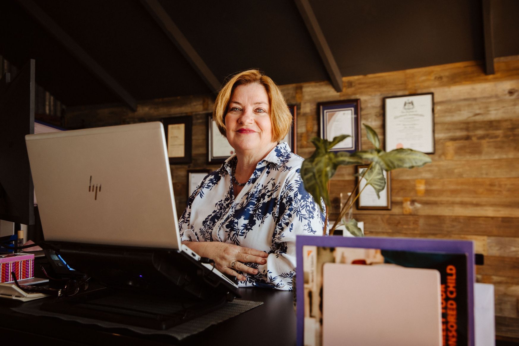 A Woman Is Sitting at A Desk in An Office Talking on A Cell Phone — Catalyst Accounting & Tax in Killarney, QLD
