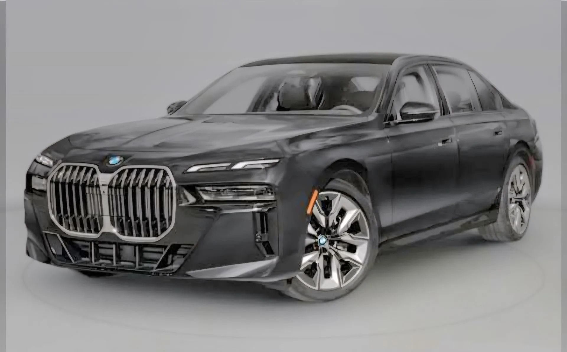 A dark grey BMW 7 Series luxury sedan angled towards the left against a plain grey background.
