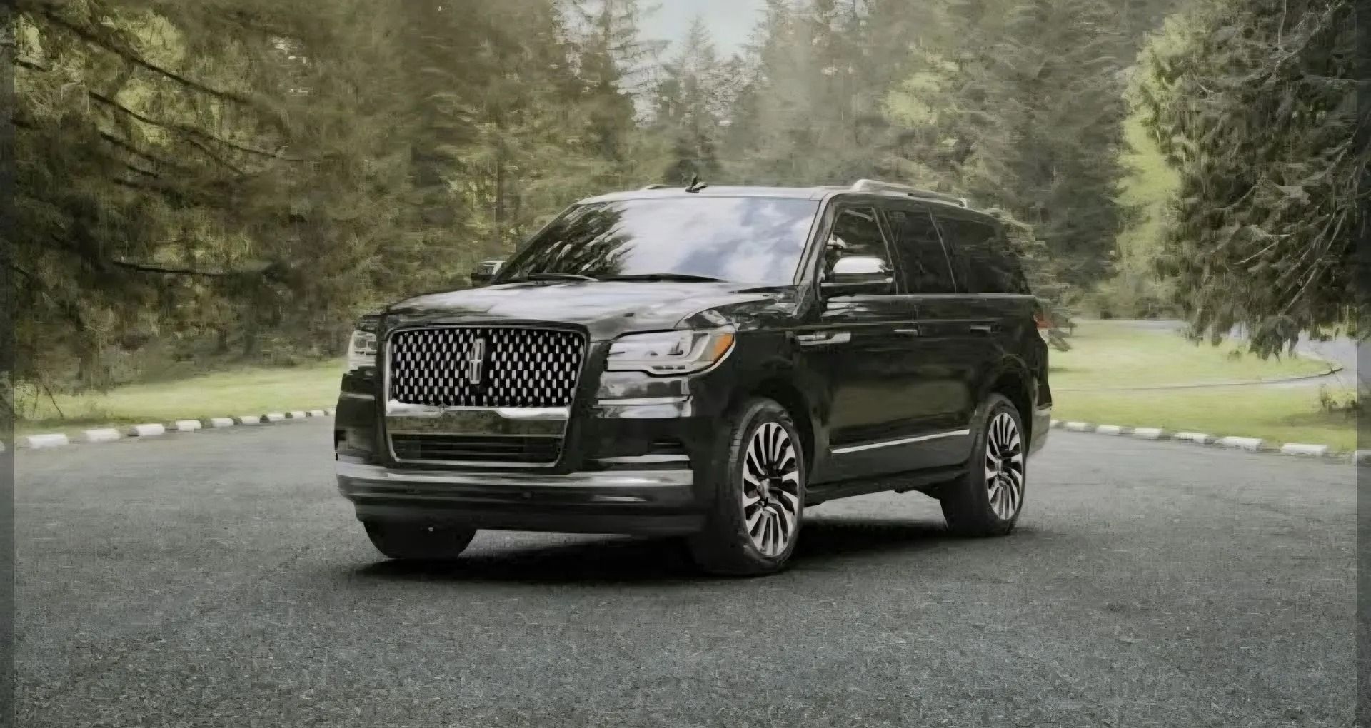 A black Lincoln Navigator SUV parked on a paved road surrounded by trees.