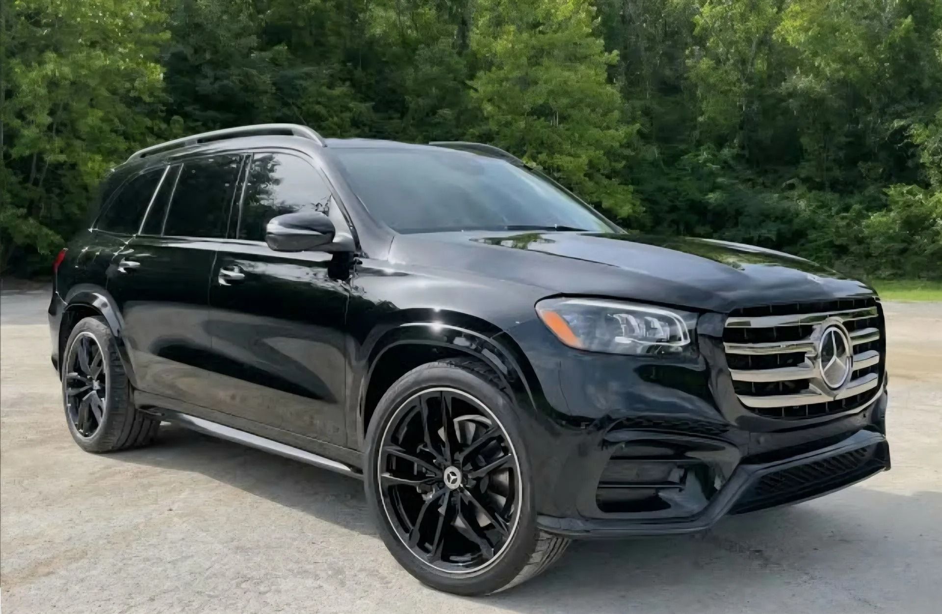 A black Mercedes-Benz GLS SUV parked outdoors with green trees in the background.
