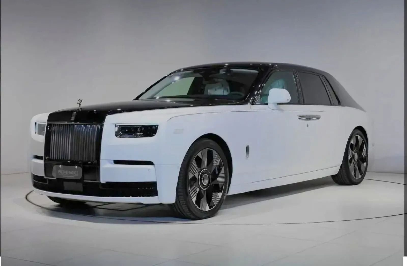 A two-tone white and black Rolls-Royce Phantom sedan parked in a minimalist white studio.