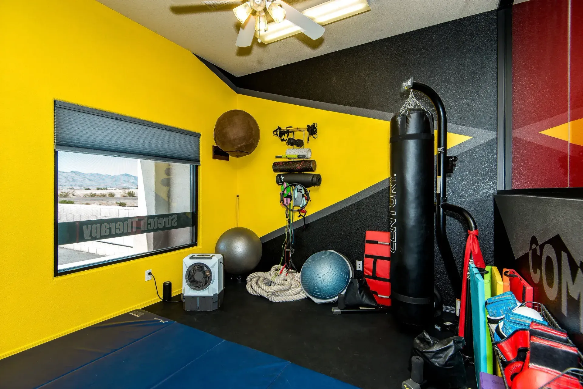 Bright Form and Function Fitness gym in Fort Mohave, AZ with yellow and black walls, exercise balls, punching bag, and workout equipment.