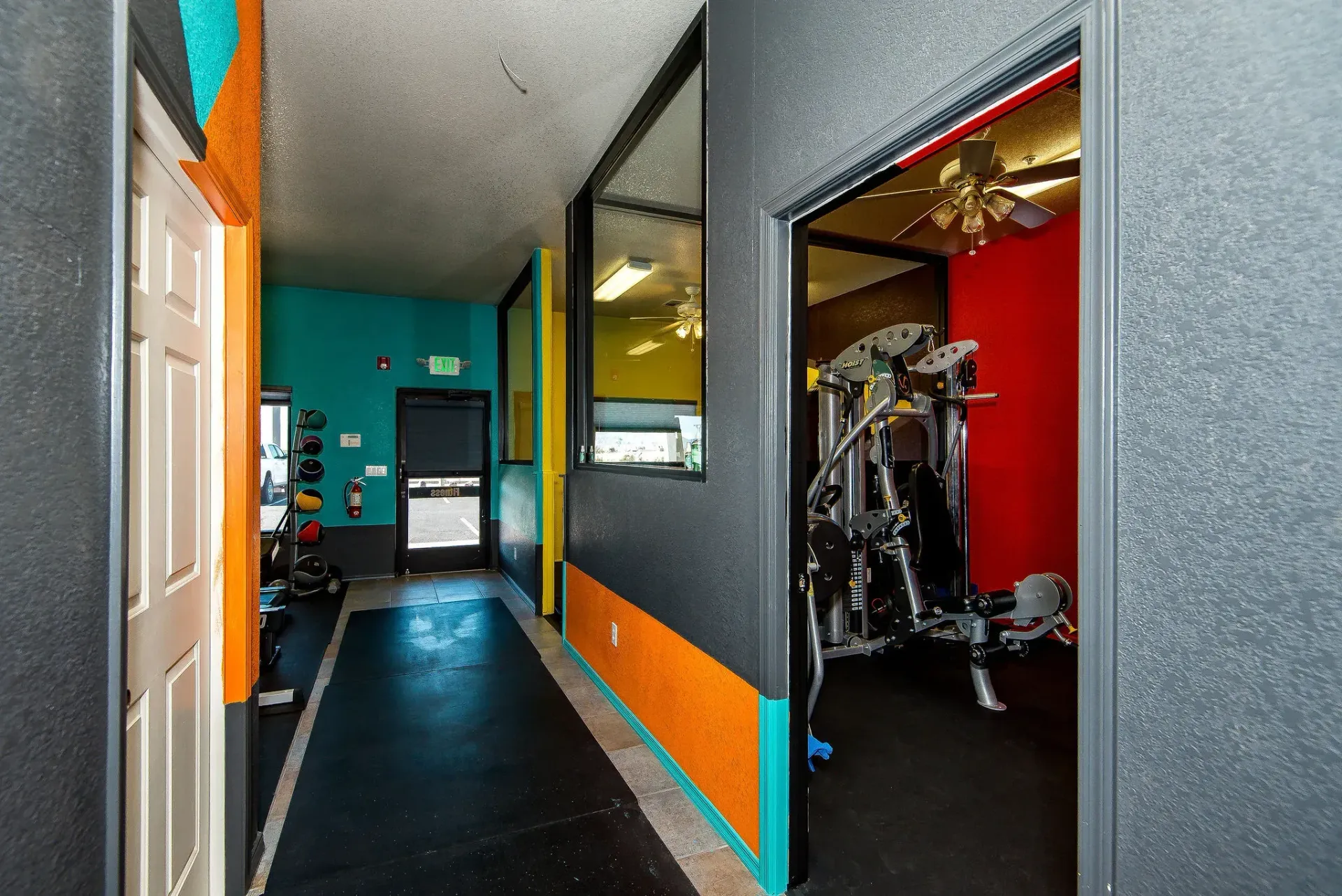 Hallway inside Form and Function Fitness gym in Fort Mohave, AZ with colorful walls and exercise equipment in side rooms