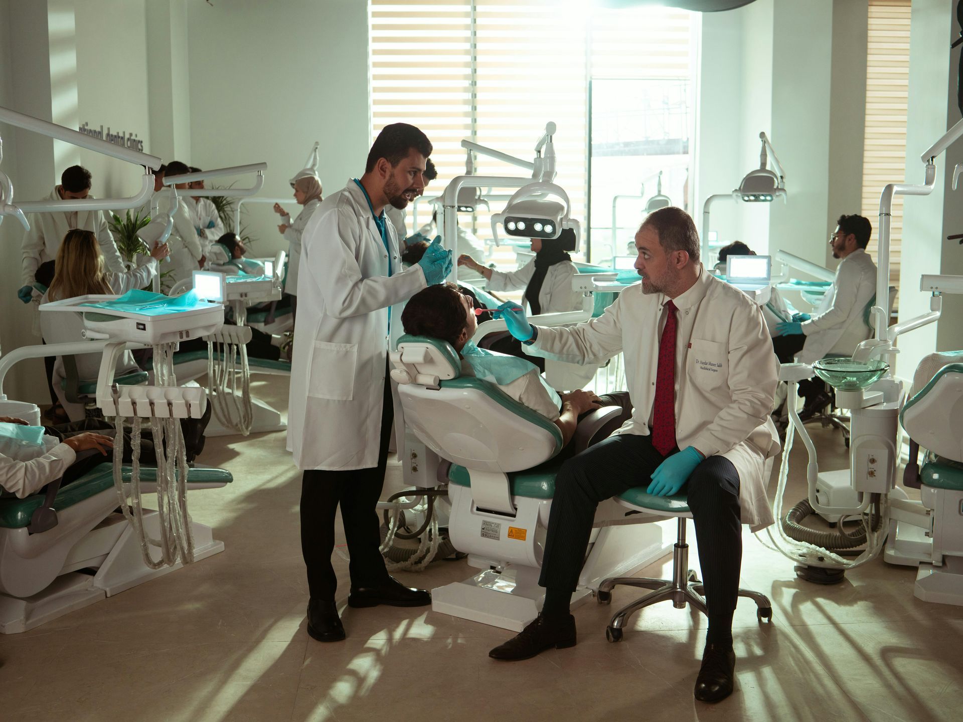 Dentists and patients in a bright dental office, using equipment.