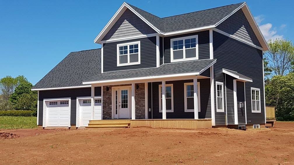 New two-story dark gray house with white trim and double garage in a dirt lot