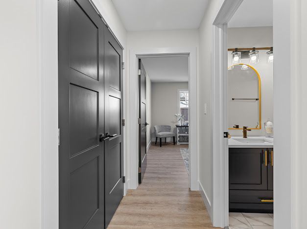 Modern hallway with gray doors, light wood floors, and a bathroom vanity visible on the right