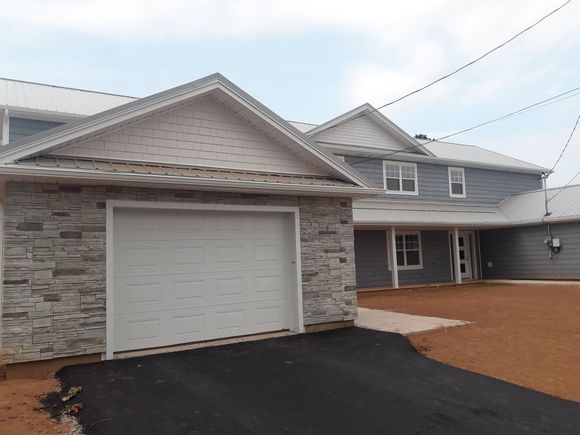 Stone-and-gray two-story house with a white garage door and paved driveway