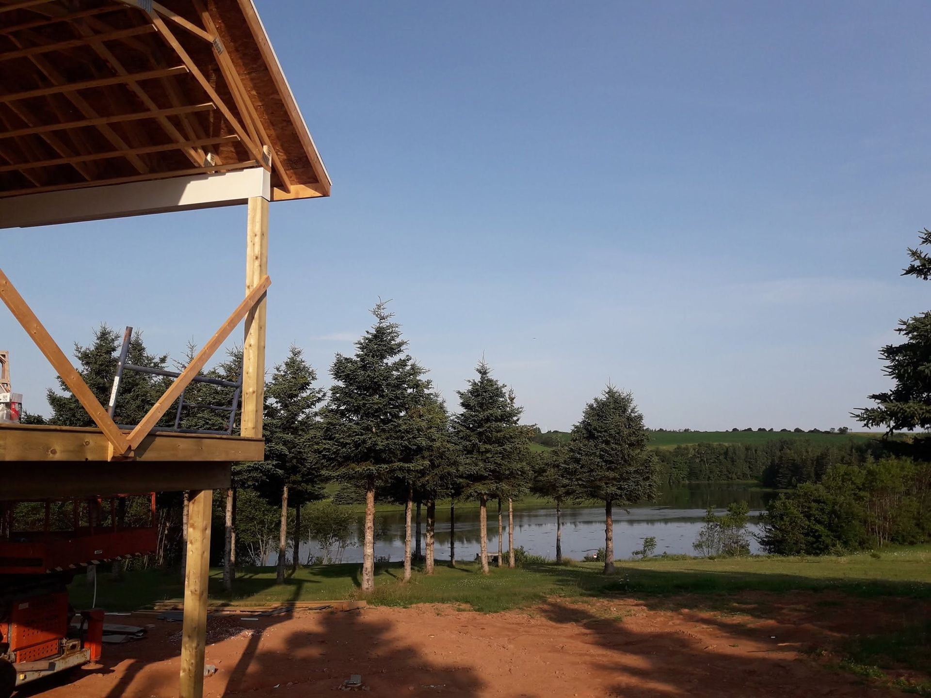 Wooden deck overlooking a lake and trees under a clear blue sky