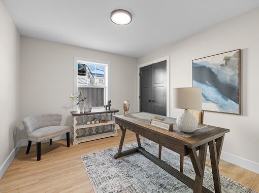 Bright home office with desk, chair, rug, wall art, and a window with shelves.
