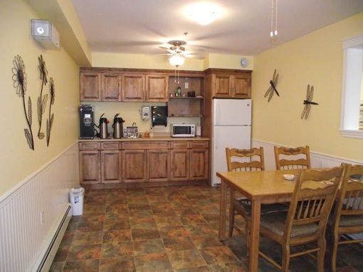 Dining room with wooden table and chairs beside a kitchen counter and cabinets, in beige tones
