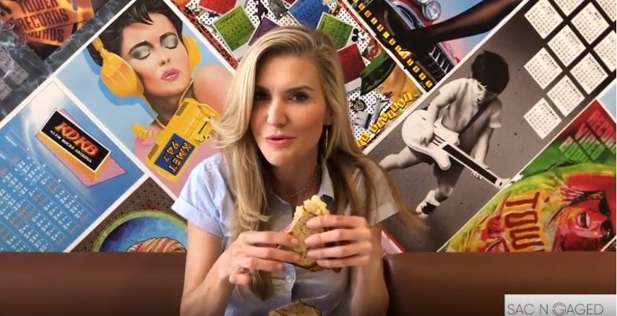 A woman is sitting at a table eating a sandwich.