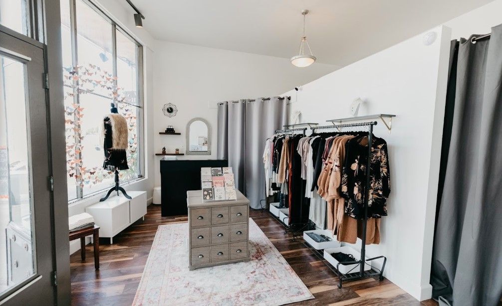 A clothes store with clothes hanging on racks and a table.