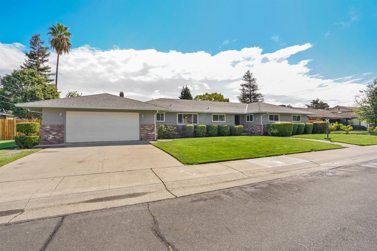 A house with a large driveway and a palm tree in the background