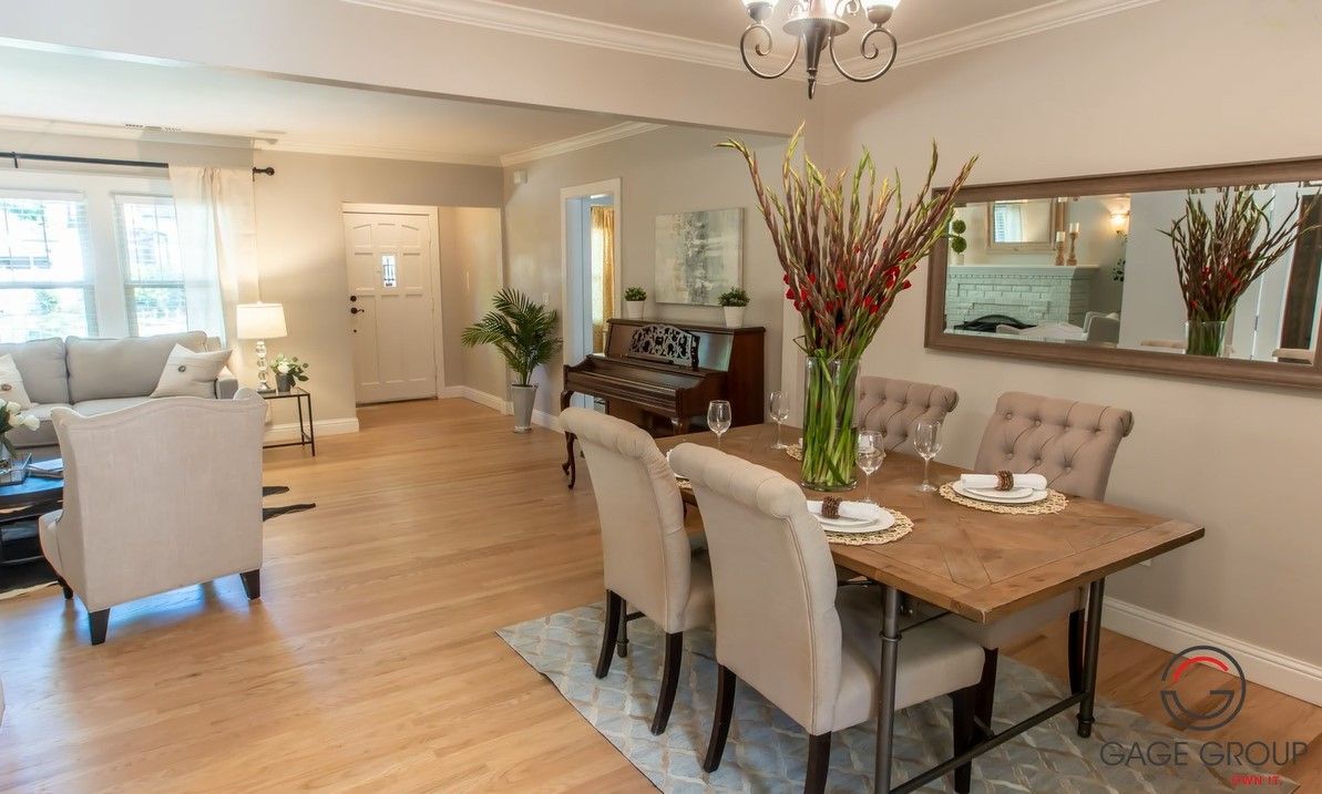 A dining room table and chairs in a living room with a large mirror.