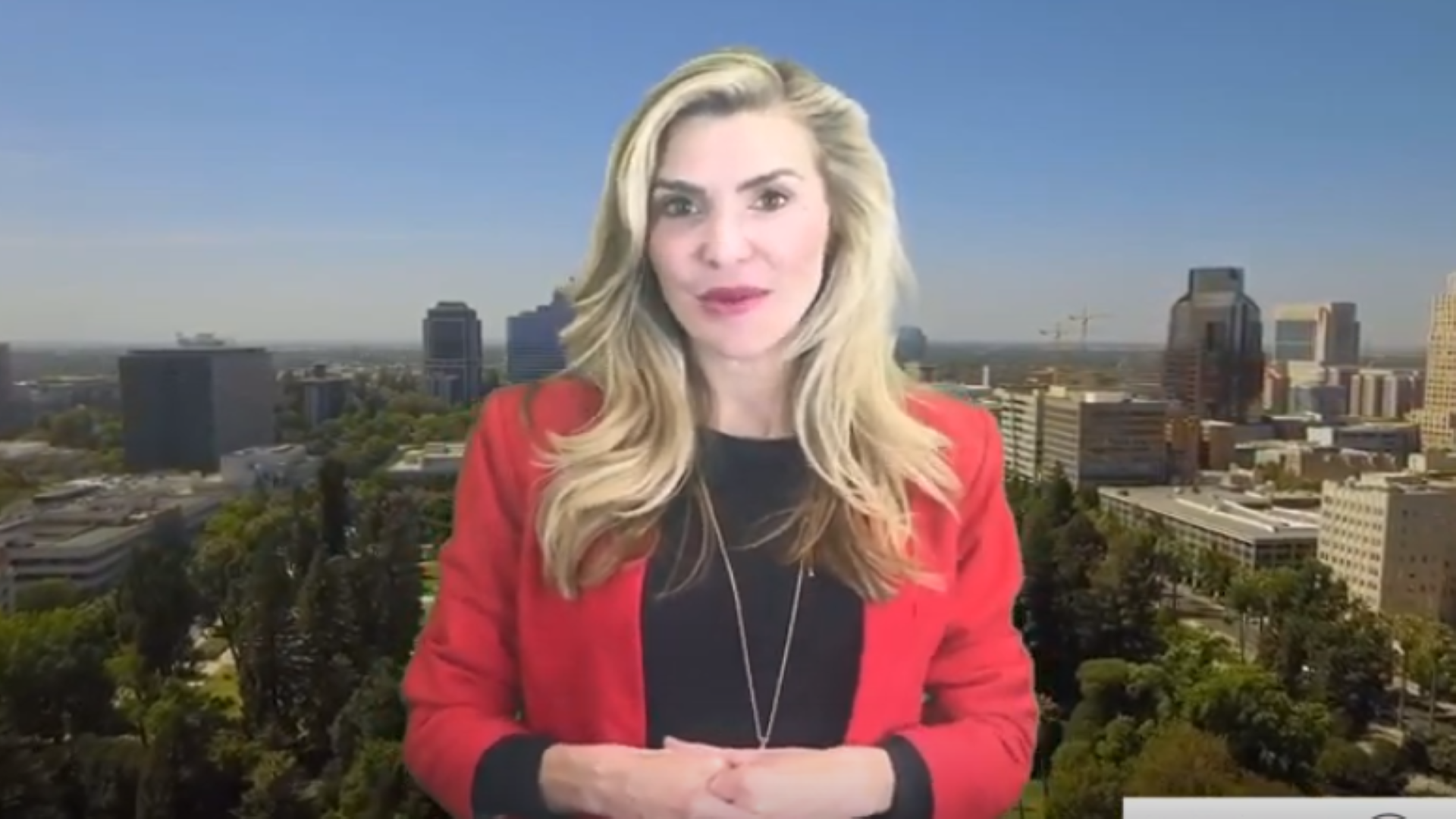 A woman in a red jacket is standing in front of a city skyline.