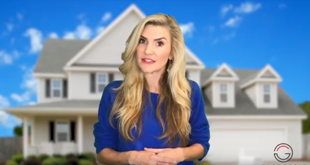 A woman in a blue dress is standing in front of a house.