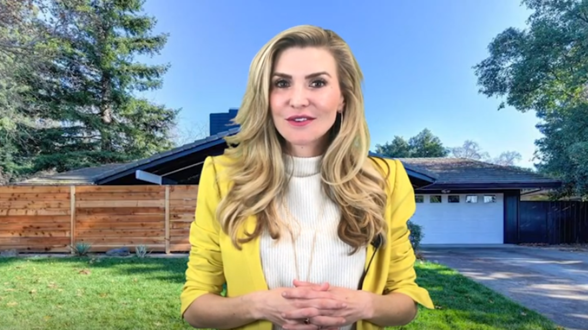 A woman in a yellow jacket is standing in front of a house.