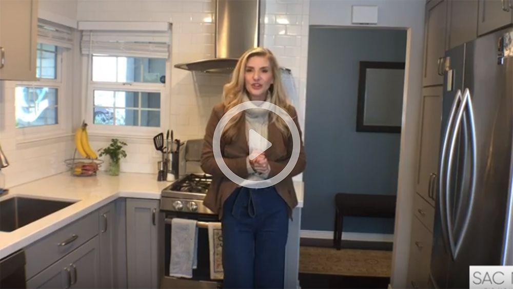 A woman is standing in a kitchen talking to a camera.