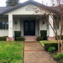 A white house with a black door and a walkway leading to it.