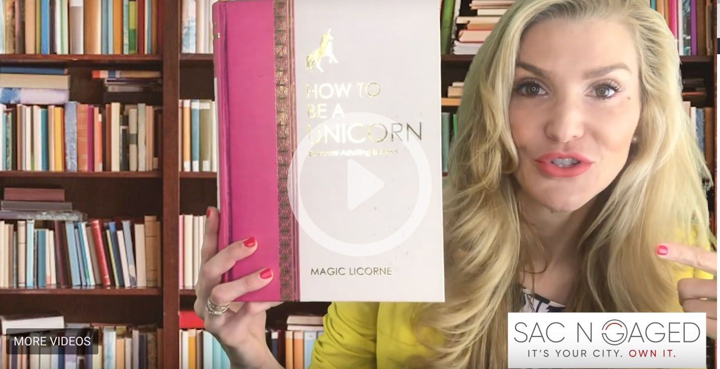 A woman is holding a book in front of a bookshelf.