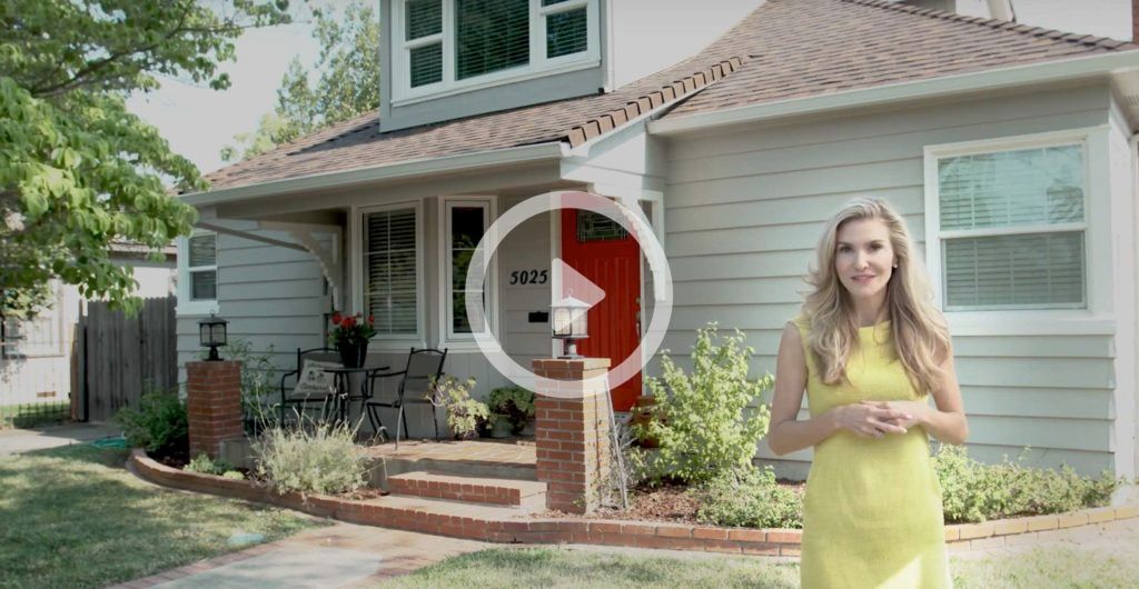 A woman in a yellow dress is standing in front of a house.