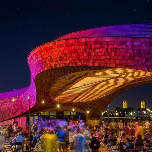 A group of people are sitting in front of a building that is lit up at night.