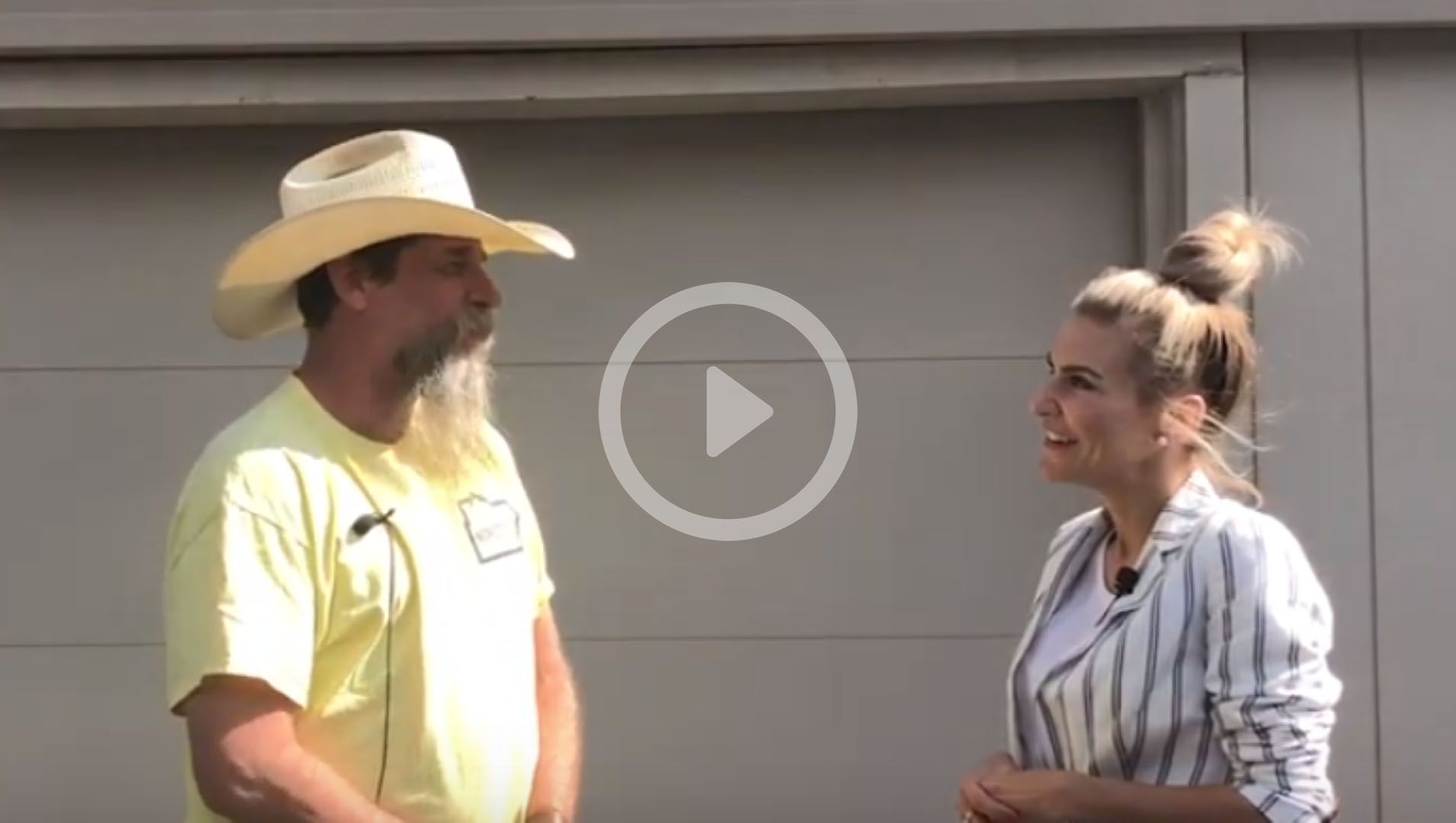 A man in a cowboy hat is talking to a woman in a striped shirt.