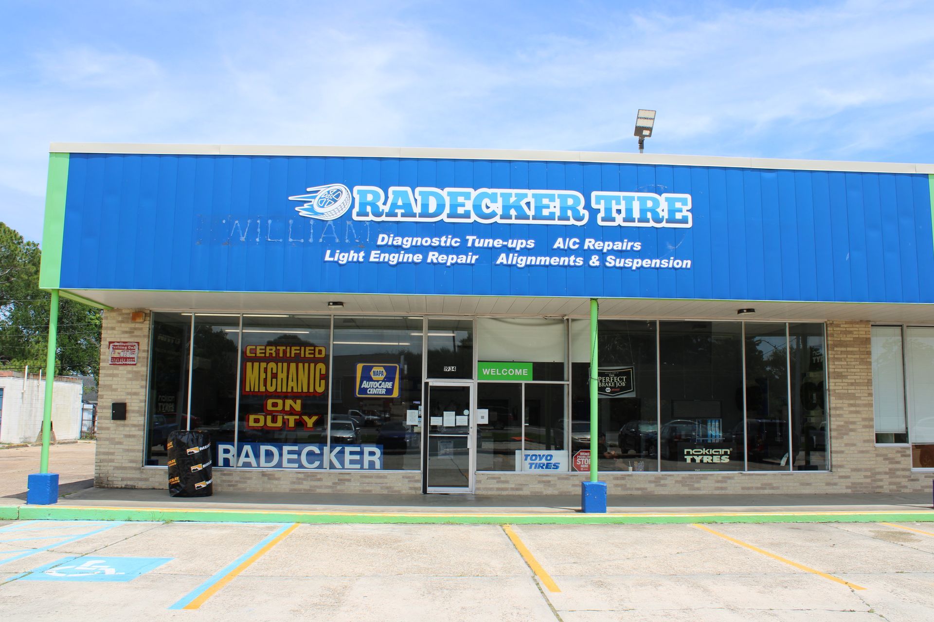 Radecker Tire storefront with blue awning and large front windows in a strip mall parking lot