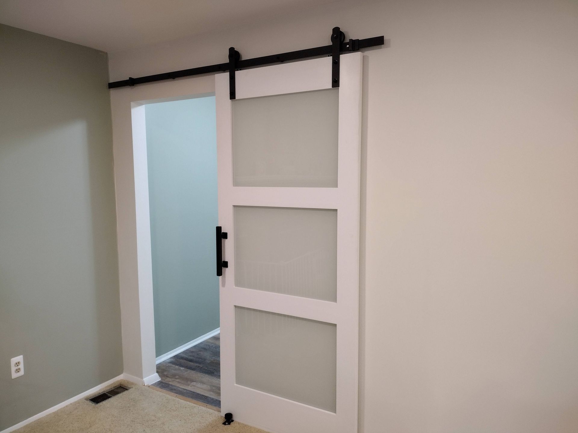 White barn-style sliding door with frosted glass panels in a beige room.