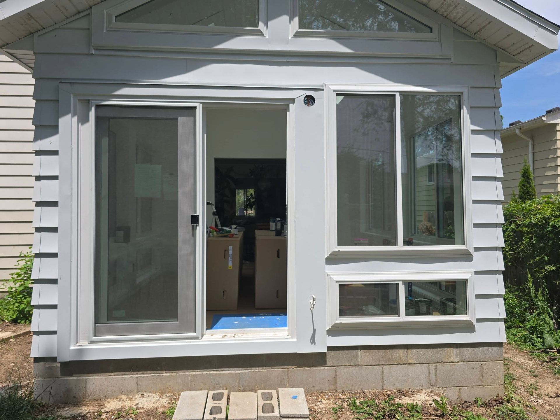Open sliding glass doors on a white house exterior with a small concrete stoop.
