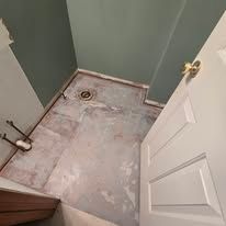 Small empty bathroom corner with a shower pan, green walls, and an open white door