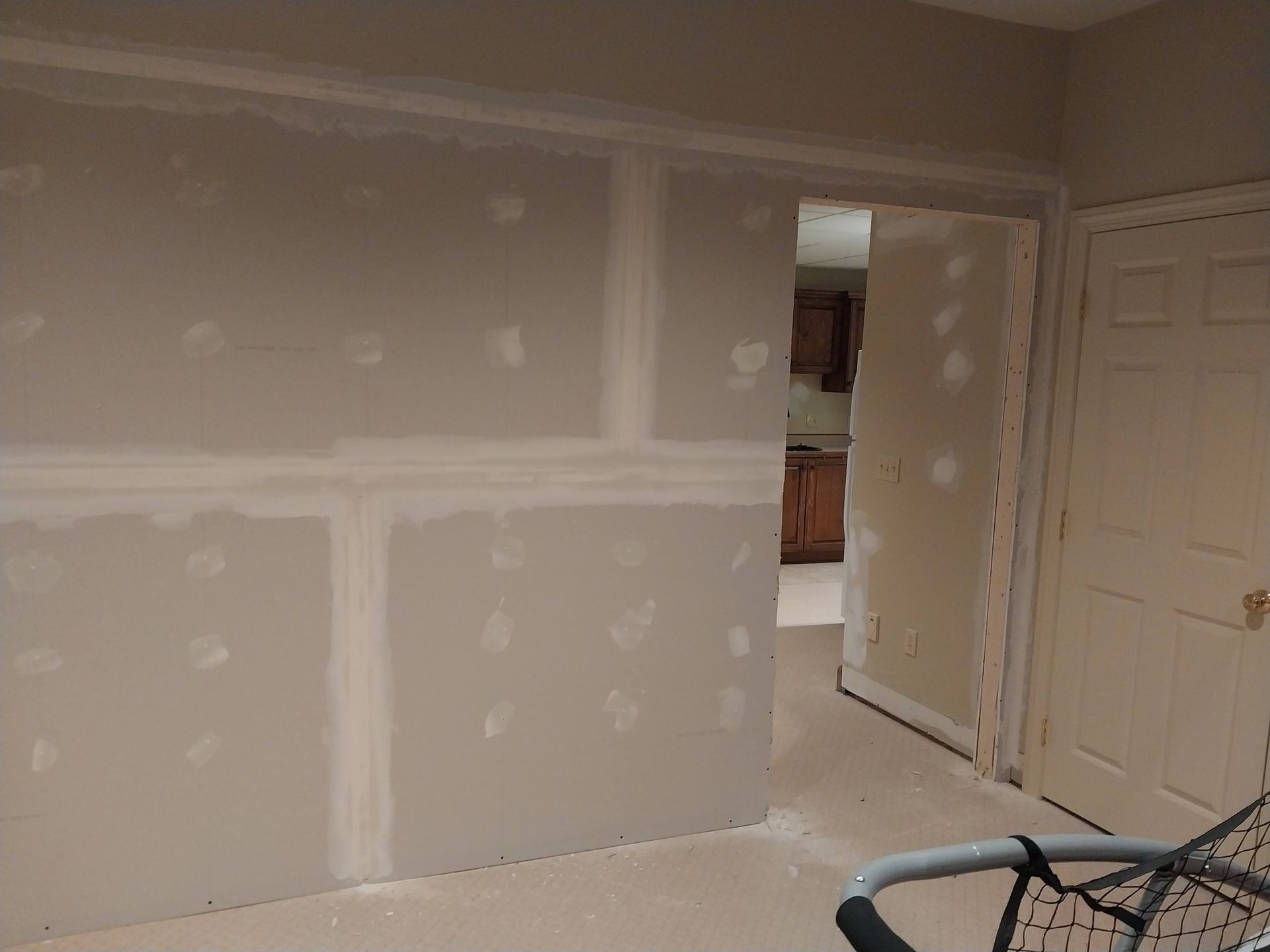 Partially finished room with drywall patches, open doorway, and a bicycle wheel in the foreground