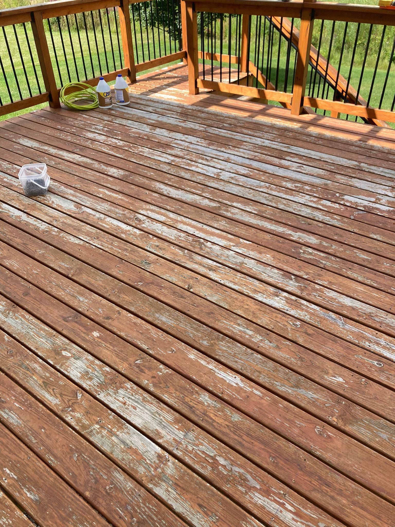 Weathered wooden deck with railings and stairs overlooking a green yard