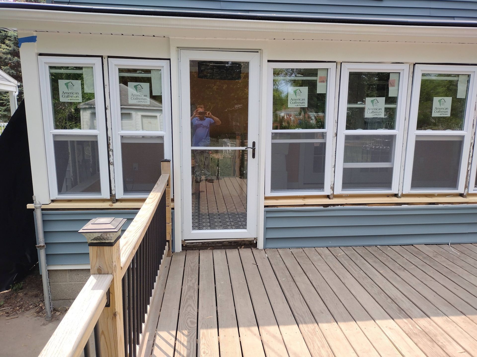 White house front porch with railing, blue siding, and a glass storm door with windows.