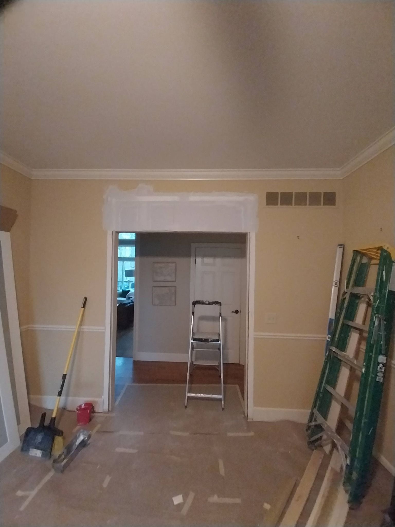 Empty room with beige walls, trim, and ladders, suggesting an in-progress renovation.