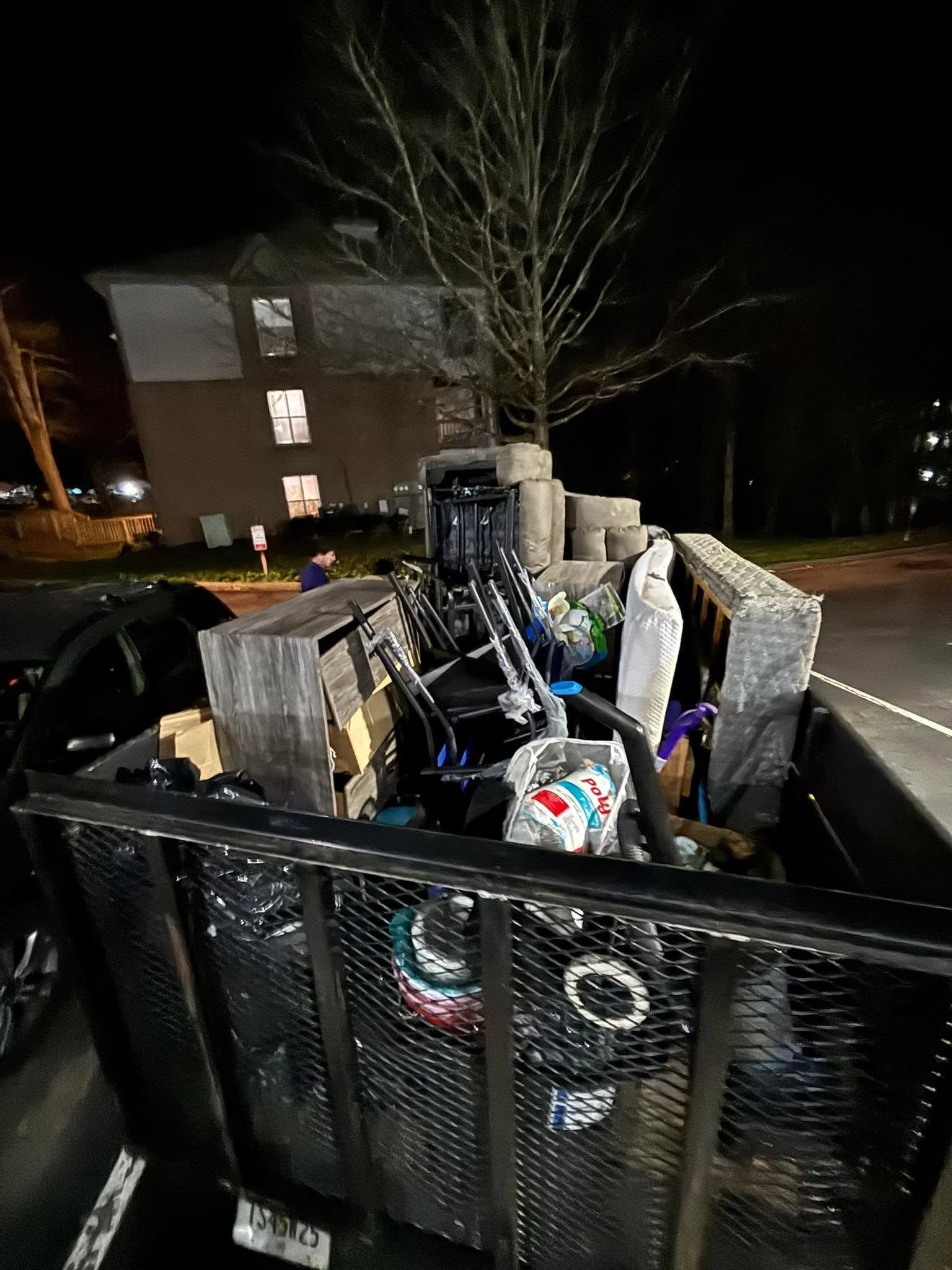 Overfilled recycling bins and trash containers on a residential street at night