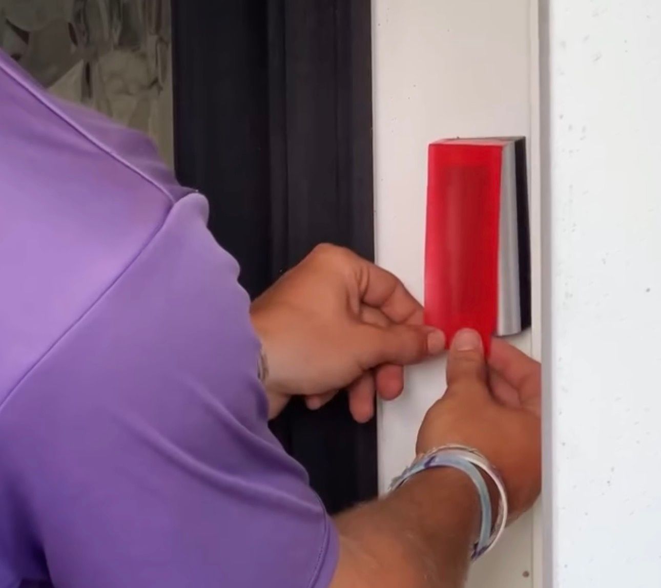 Hands pressing a red access button beside a doorway