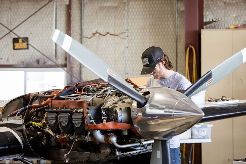 Technician repairing aircraft engine in hangar