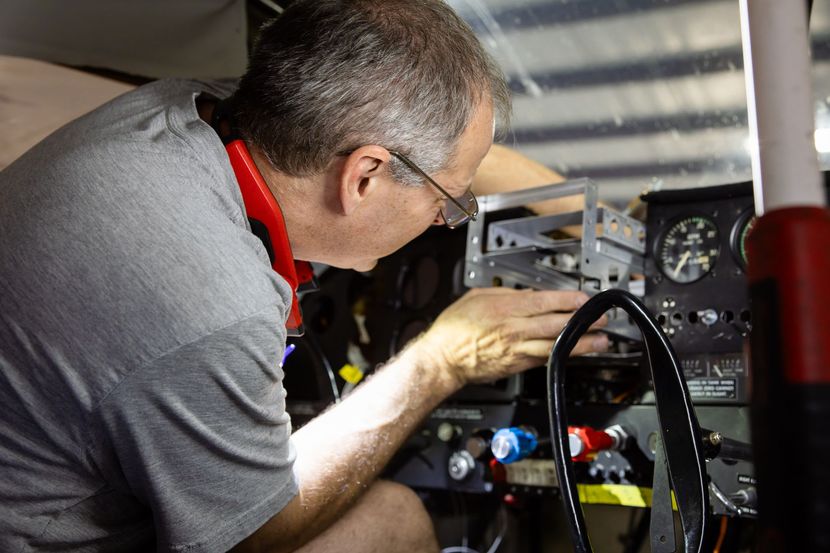 Technician wiring avionics inside cockpit panel
