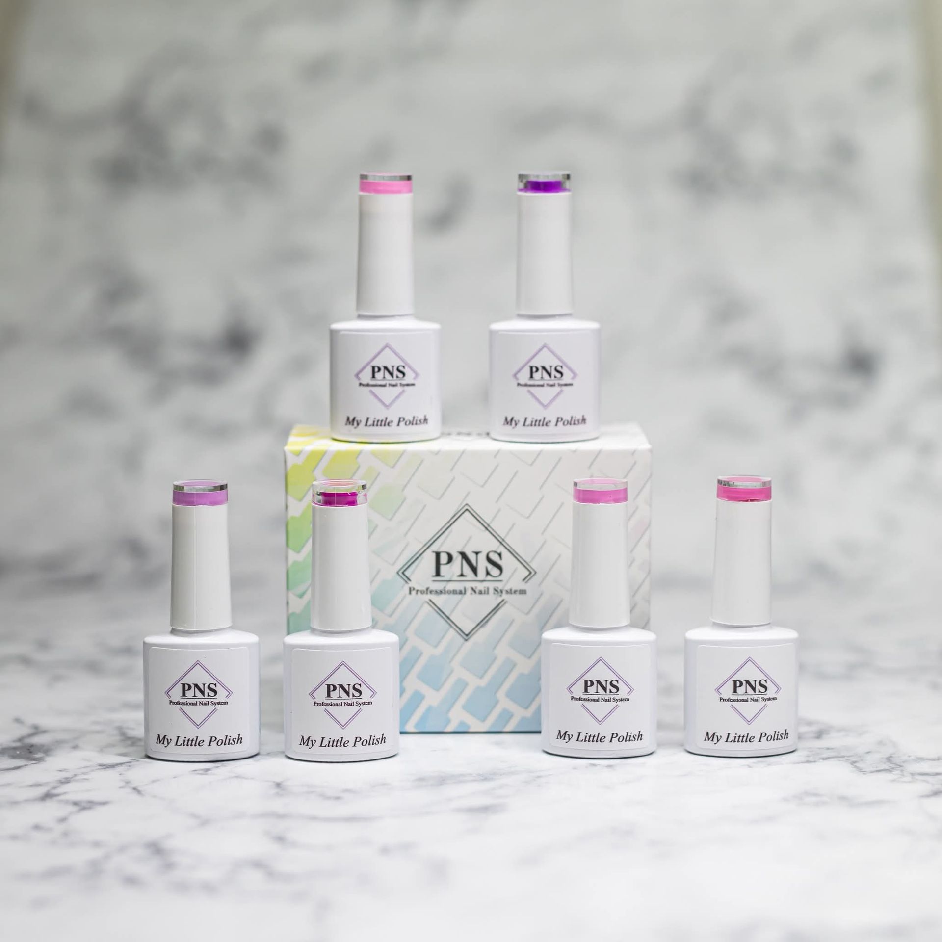 Zes flesjes PNS gelnagellak met verschillende roze en paarse dopjes, uitgestald op een wit marmeren oppervlak met een doos.
