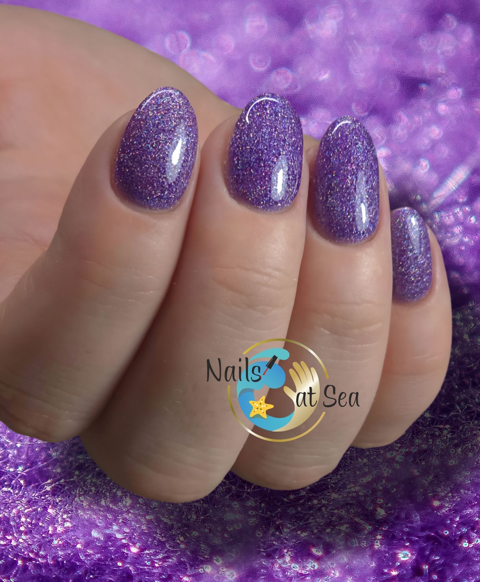 Een vrouwenhand met paarse nagels en de woorden nagels op zee