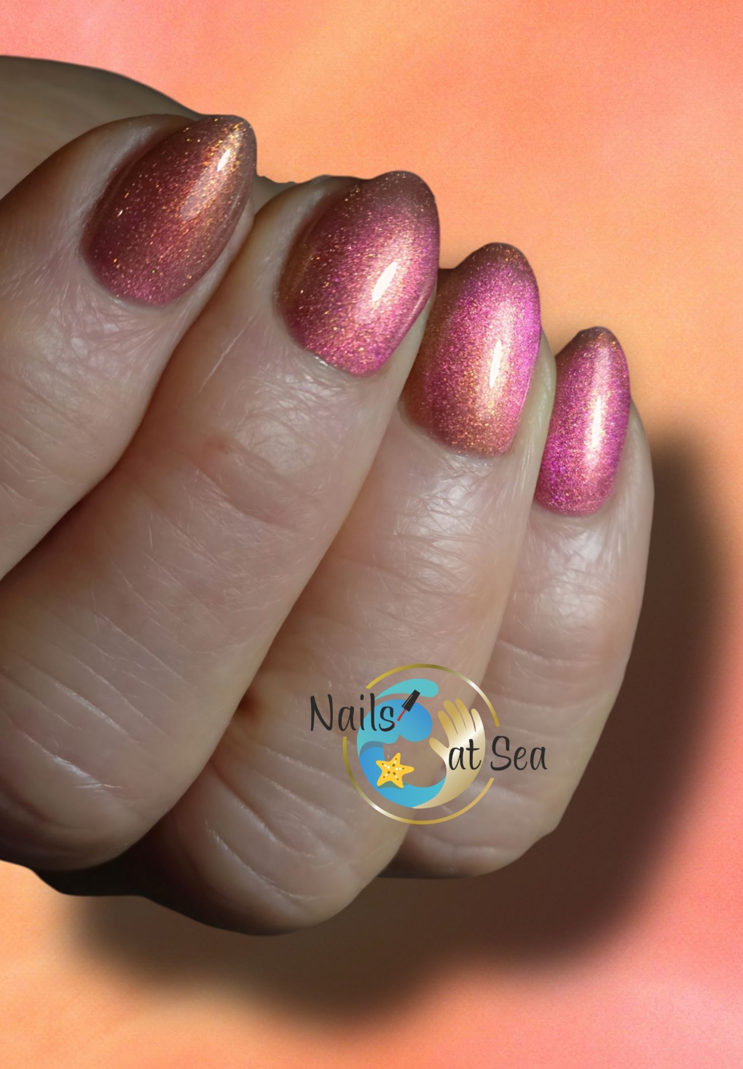 Een close-up van de nagels van een vrouw met het logo van Nails by the Sea