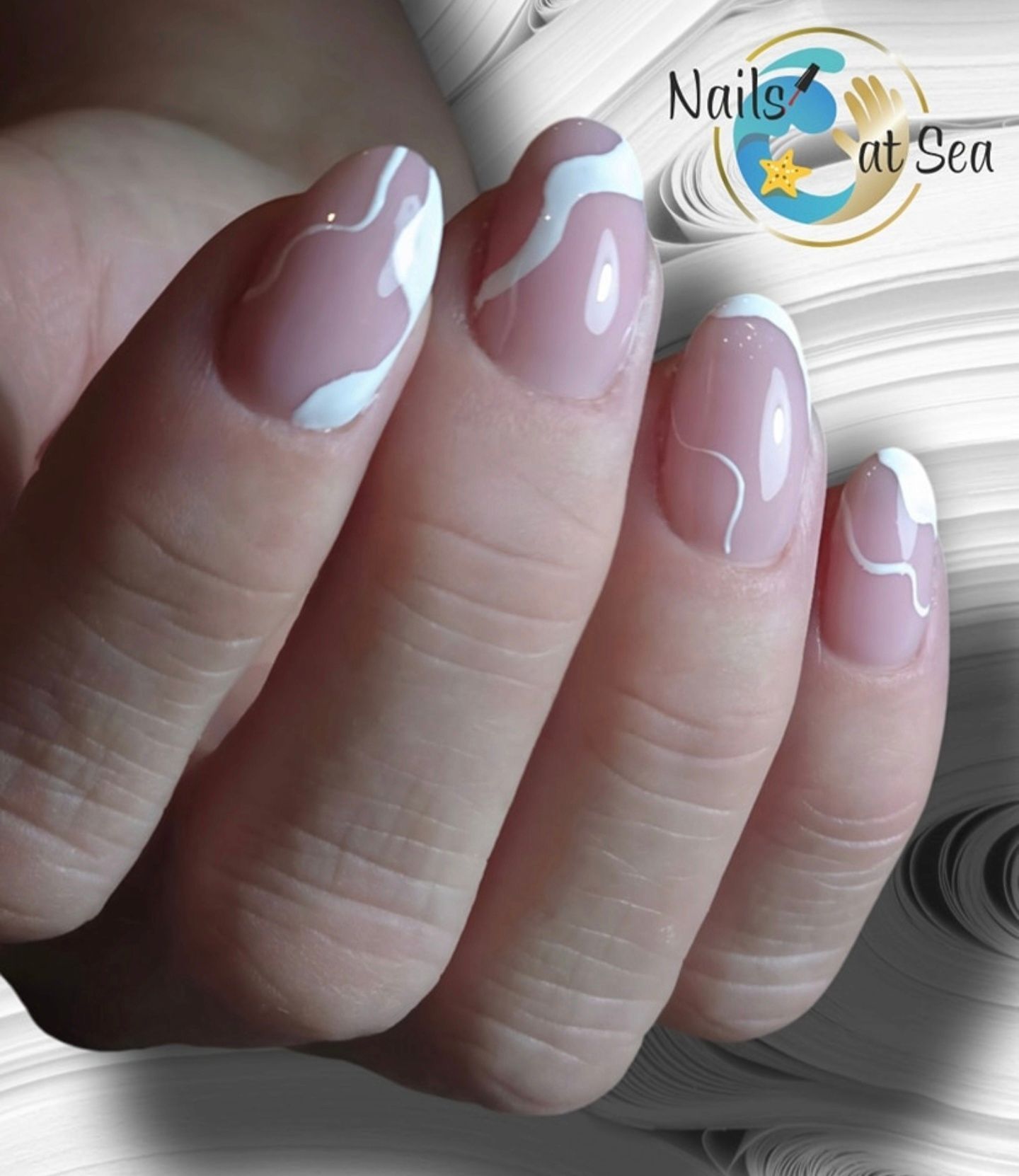 Een hand met amandelvormige nagels, een nude basis en artistieke, witte, wervelende French manicure designs.