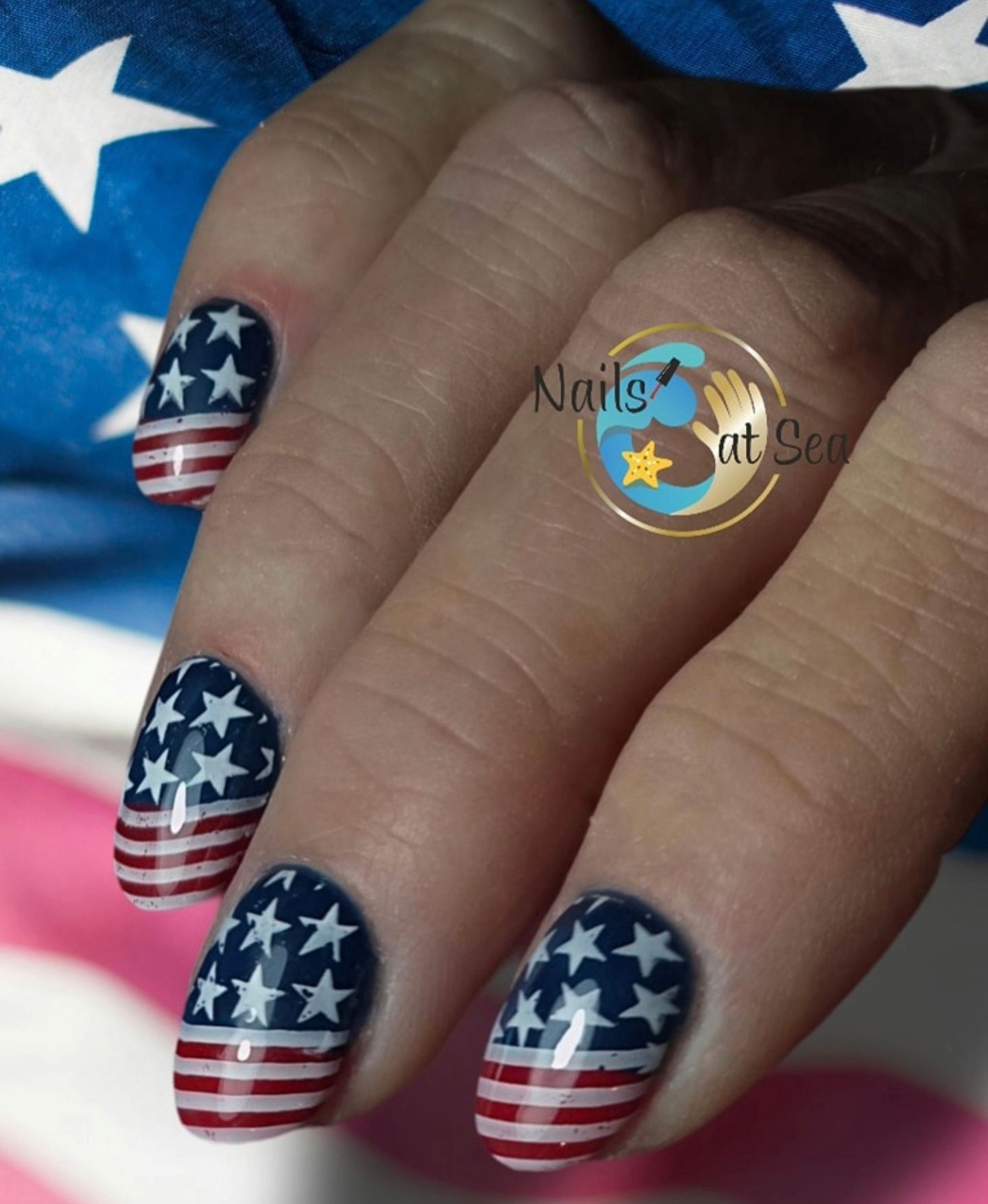 De vingernagels van een persoon zijn beschilderd met een patroon van de Amerikaanse vlag: witte sterren op een blauwe achtergrond en rood-witte strepen.