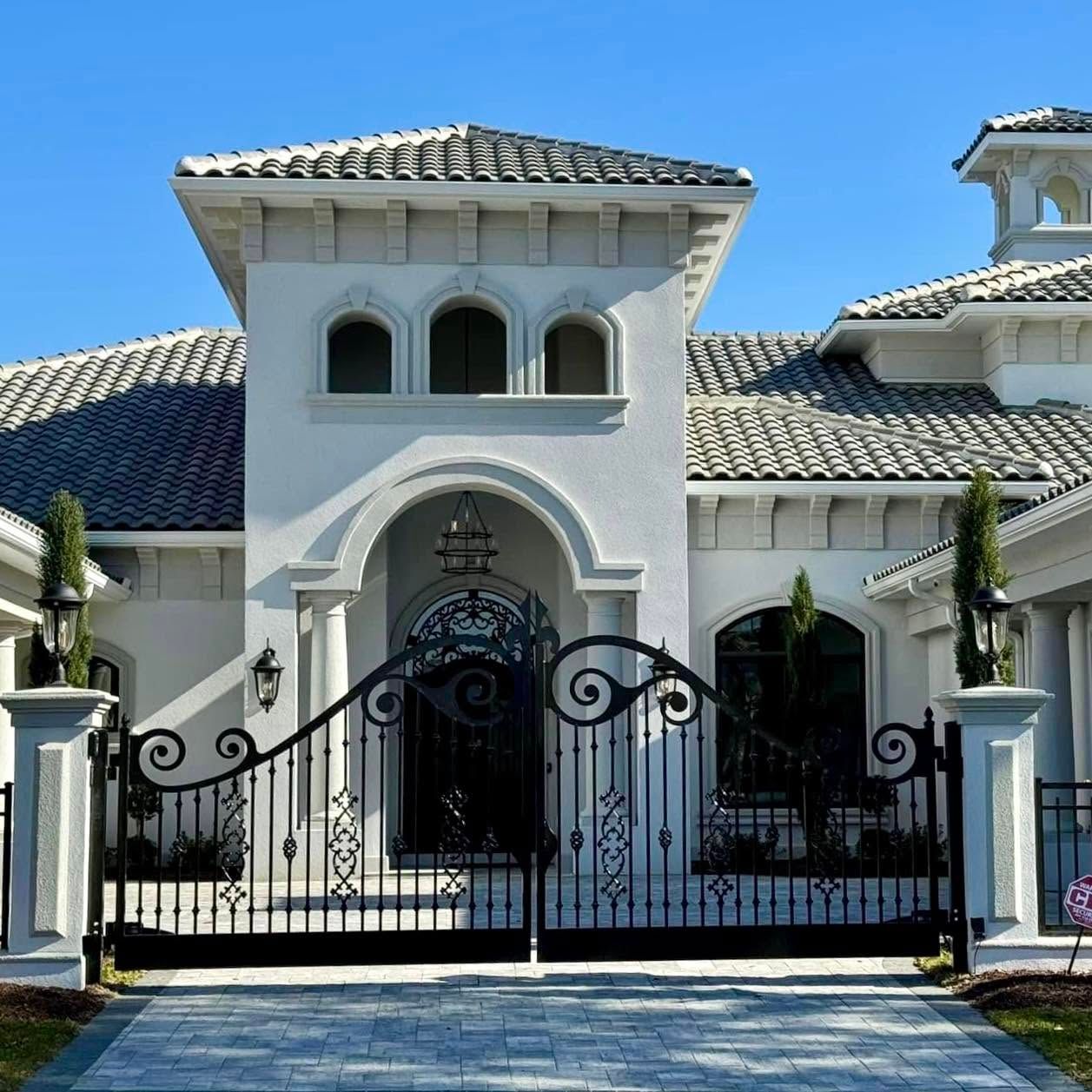 White Mediterranean-style house with arched entry and wrought-iron gate under a blue sky