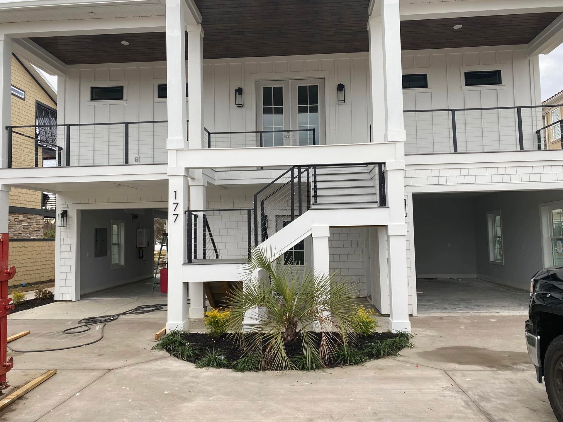 Two-story apartment building with exterior stairs, white railings, and covered parking underneath