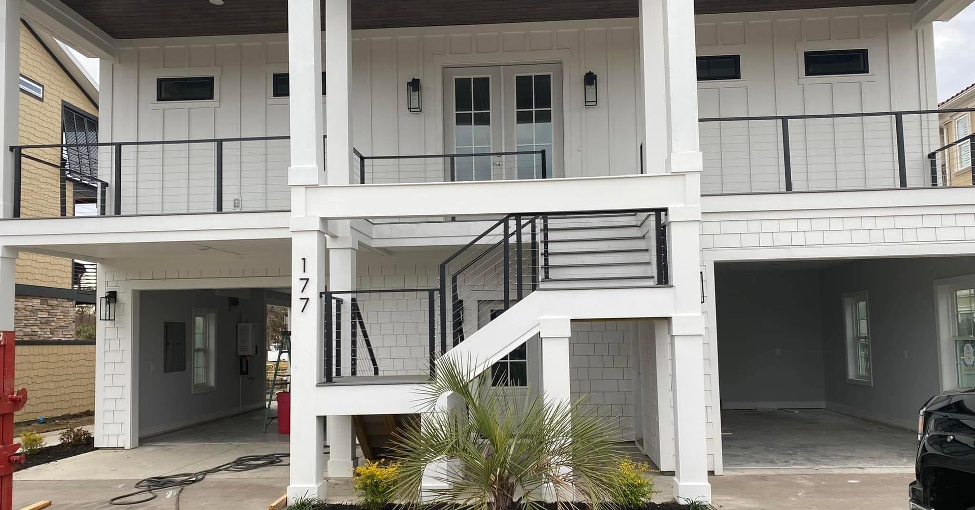 Two-story apartment building with white balconies and stairways, viewed from the front