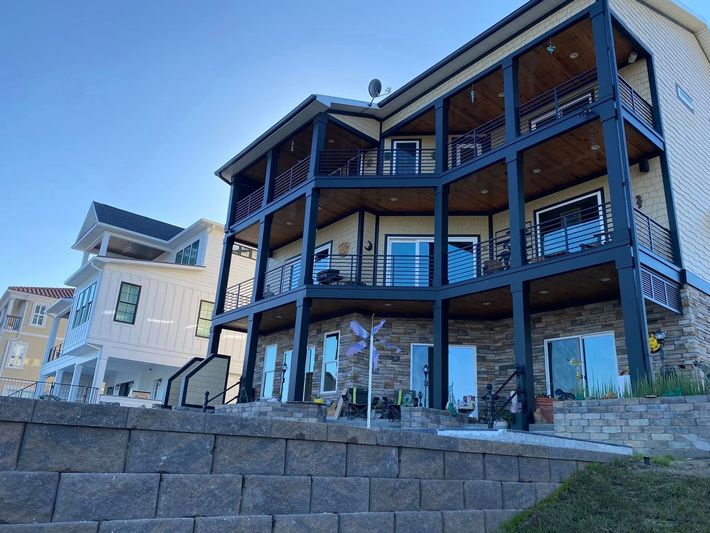 Stone retaining wall and modern multi-level house with balconies on a sloped lot