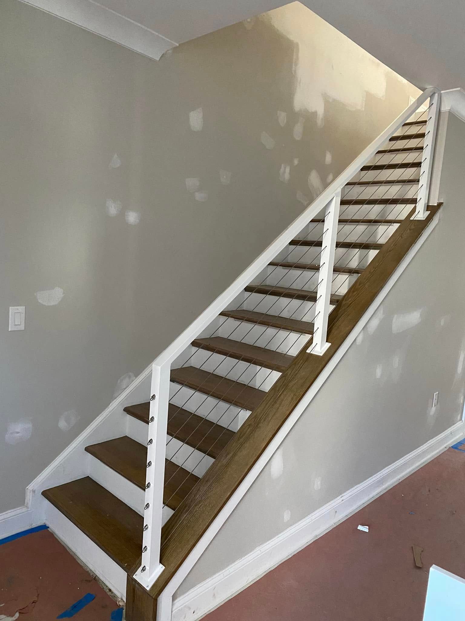 Indoor staircase with white railings and brown carpeted steps against gray walls